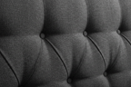 Close-up of charcoal boucle fabric texture with deep button tufting