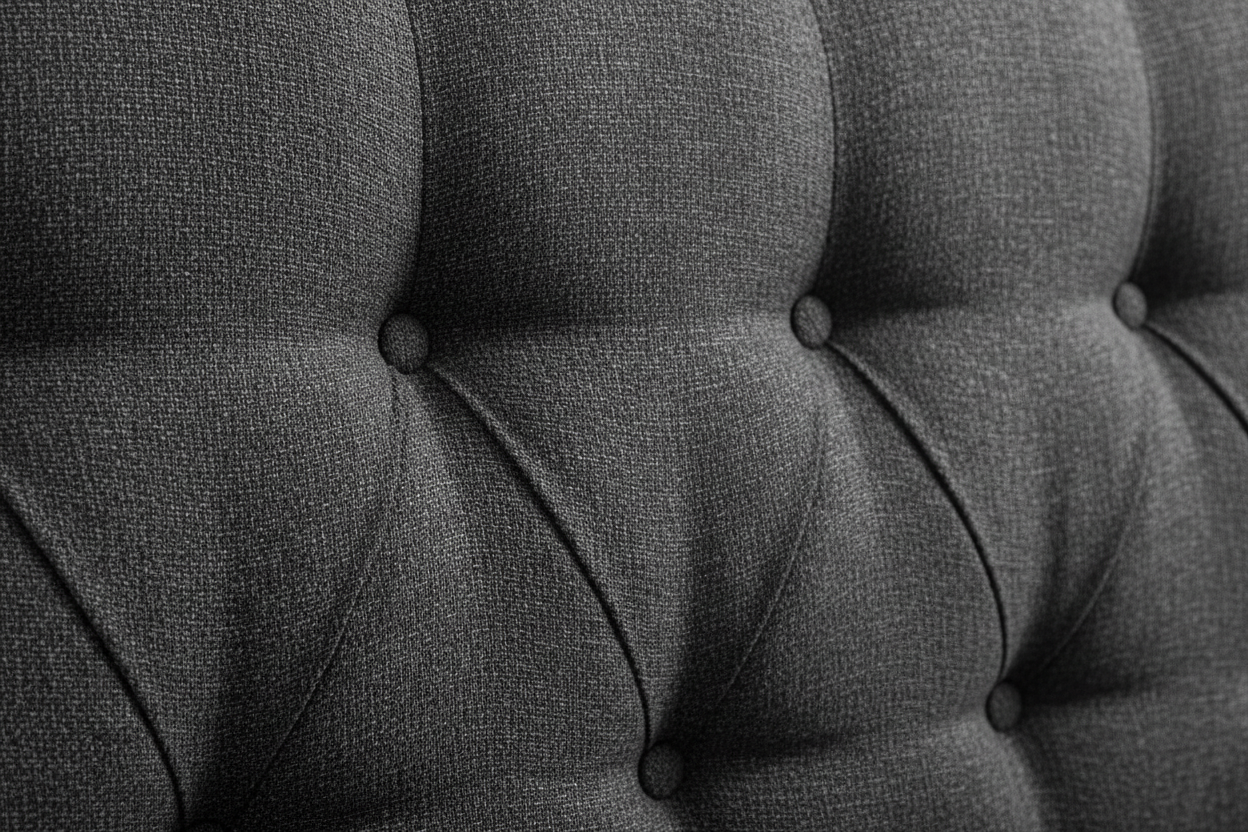 Close-up of charcoal boucle fabric texture with deep button tufting