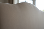Close-up of mink beige fabric texture on curved divan bed headboard