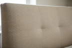 Close-up of oatmeal linen fabric texture on ottoman bed headboard