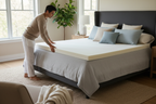 Person placing memory foam topper onto a bed