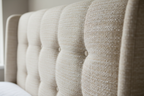 Close-up of cream fabric texture on divan bed wingback headboard